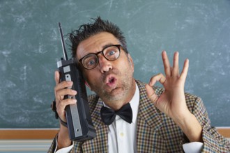 Nerd silly private investigator with retro walkie talkie on teacher balckboard