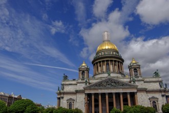 Building with golden dome under blue sky with clouds and trees in the foreground, saint petersburg,