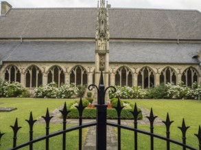 A well-kept courtyard with Gothic architecture, flower beds and a decorative fence in the