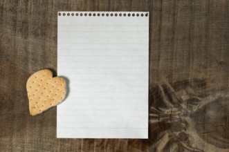 Heart shape cookie on wooden background and white paper sheet