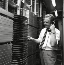 Telephony in the 1970s. A man in a room with an automatic switchboard connecting the calls through