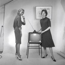 Television in the 1950s. Two young women are standing dressed in a typical 50s dress beside a