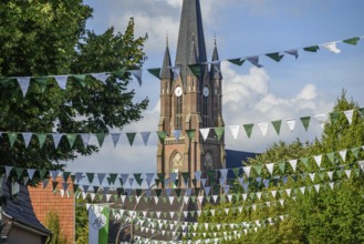 Church with high tower and flags, surrounded by trees, borken, münsterland, germany