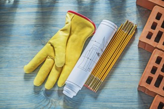 Blueprints safety gloves red bricks wooden meter on wood board bricklaying concept