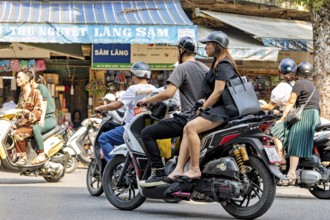 People ride scooters through a busy city shopping street during the day, people on scooters ride
