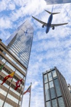 Plane reflecting on modern glass building facade while flying through the sky, Hong Kong island.