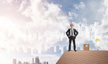 Young businessman in suit and helmet on roof edge. Mixed media