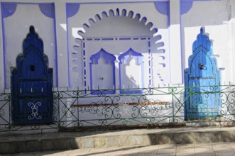 Chefchaouen, Rif Mountains, Morocco, Detail of blue ornamental doors with shadows on a white wall,