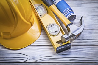 Claw hammer building helmet blue rolled engineering drawings construction level on wooden board