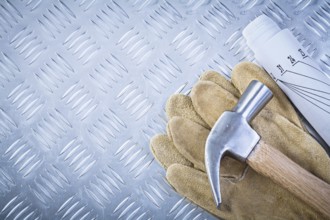 Claw hammer leather safety gloves blueprints on fluted metal sheet construction concept