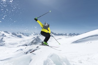 A skier in full sports equipment jumps into the abyss from the top of the glacier against the
