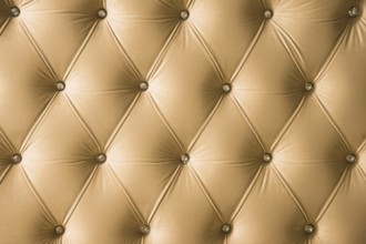 Beige soft textile background with symmetrical buttons on the corners of diamonds. Soft and