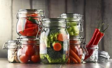 Jars with marinated food and organic raw vegetables