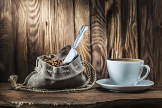 White coffee cup and bag of beans with scoop on vintage wood background