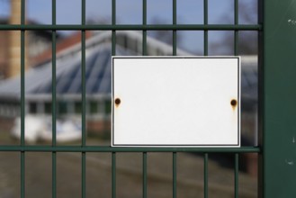 Unlabelled white sign on a fence with space for text