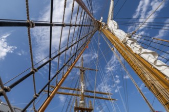 Low angle view of sailboat wooden ship masts and rigging under blue sky with clouds