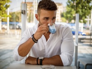 Attractive Young Man Drinking Novelty Blue Coffee while Sitting in a Bar with Serious Expression