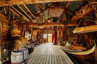 A wooden interior features tightly packed fishing equipment and a small boat, suggesting a seashore