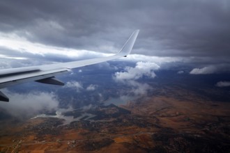 Aircraft wing in a cloudy stormy clouds sky flying