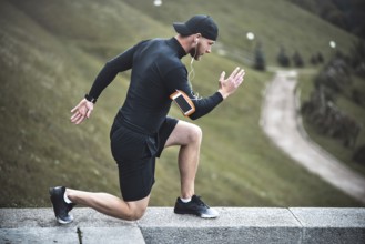 Young caucasian male jogger with fitness tracker attached to arm do warming up before jogging