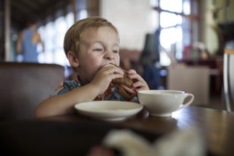Little boy in a cafe eating big tasty sandwich. Hungry child