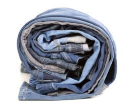 Different jeans rolled up on a white background