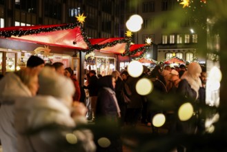 Large crowds of people at a brightly lit Christmas market at night, Cologne, North
