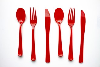 Single use red plastic cutlery on a white background. Concept: Ban single use plastic