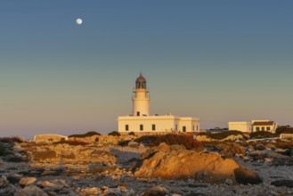 A view of the Cap de Cavalleria Lighthouse on Menorca at sunset with a full moon rising