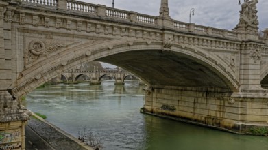 A grand stone bridge with intricate carvings spans over a calm river beneath a cloudy sky, Vittorio