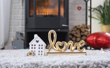 Key to house with keychain against background of fireplace stove with fire and firewood in