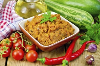 Caviar squash in a clay bowl, tomatoes, red pepper, zucchini, napkin, garlic, vegetable oil on a
