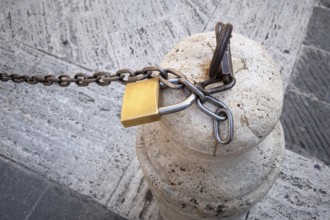An image of a chain with a lock on a stone pillar