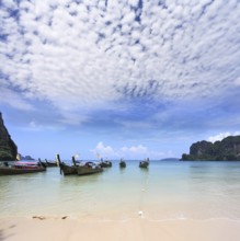Light cirrus clouds over the warm sea. Picturesque native boat Longtail waiting on the beach the