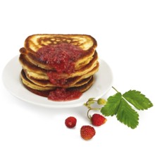 A stack of pancakes on a white plate with strawberry jam, strawberries on a branch, green leaf