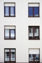 The façade of a residential building with windows reflecting the surroundings