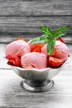 Ice cream with strawberries and leaves of mint in the iron bowl