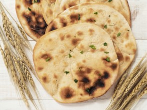 Fresh naan bread on white wooden background with copy space. Top view of several perfect naan