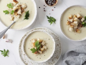 Cauliflower potato soup puree on white marble tabletop, Creamy cauliflower soup with toasted bread
