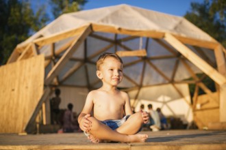 Theme is yoga and children. Caucasian Boy child sitting barefoot cross-legged in lotus position on