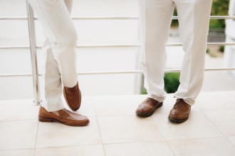 The legs of two men standing on the balcony, close-up. The groom and his best man during the