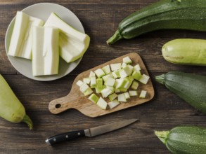 Zucchini harvest. Slices farm organic zucchini cubes for freezing on woodencutting board over brown
