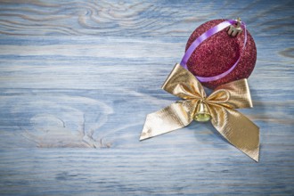Red Christmas ball golden bow on wooden board holidays concept