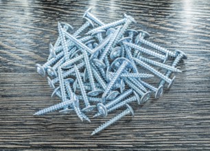 Stack of stainless screws on wooden board