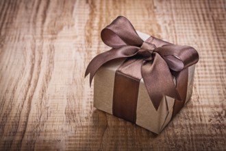 Single square vintage gift box qith brown bow on old wooden board