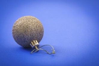 Single gold colored christmas ball on blue background