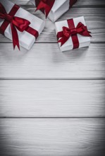 Present boxes with red ribbons on wooden board holidays concept