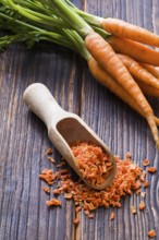 Wooden scoop with seasoning made of dried milled carrots. Tasty condiment for cooking. From above