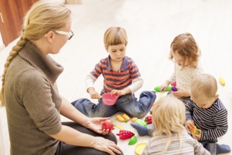 Children with teacher in kindergarten playing cooks