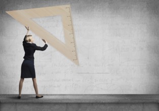 Woman holding big ruler on wall background. Testing and examination concept. Businesswoman